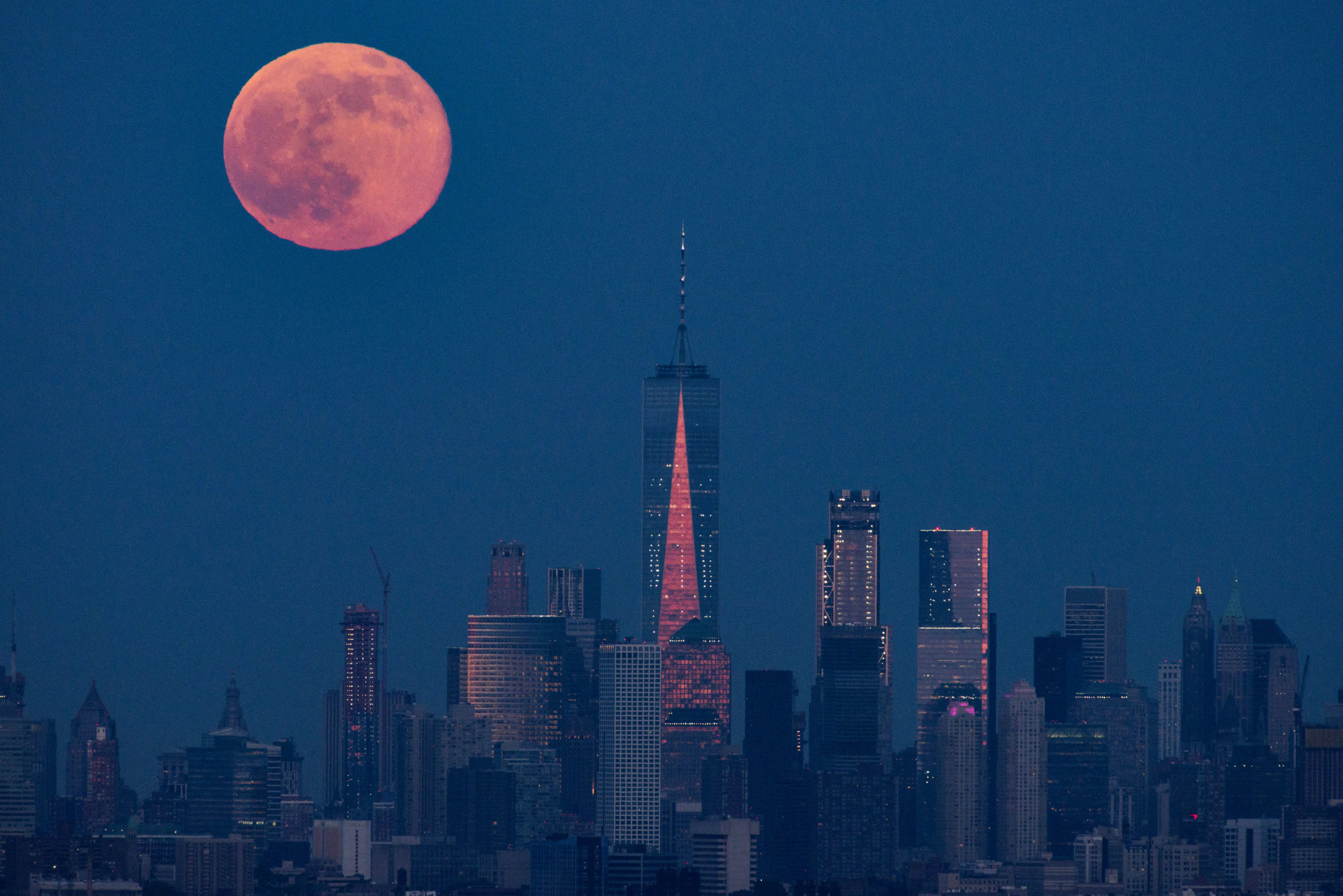 An orange moon behind the NYC skyline, centered on Freedom Tower