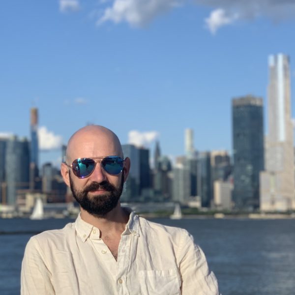 Parker in mirrored sunglasses with the NYC skyline behind him